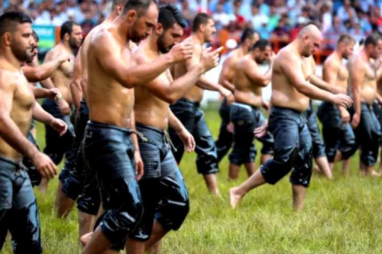 “Kırkpınar oil wrestlers walking on grass during traditional peşrev ceremony”