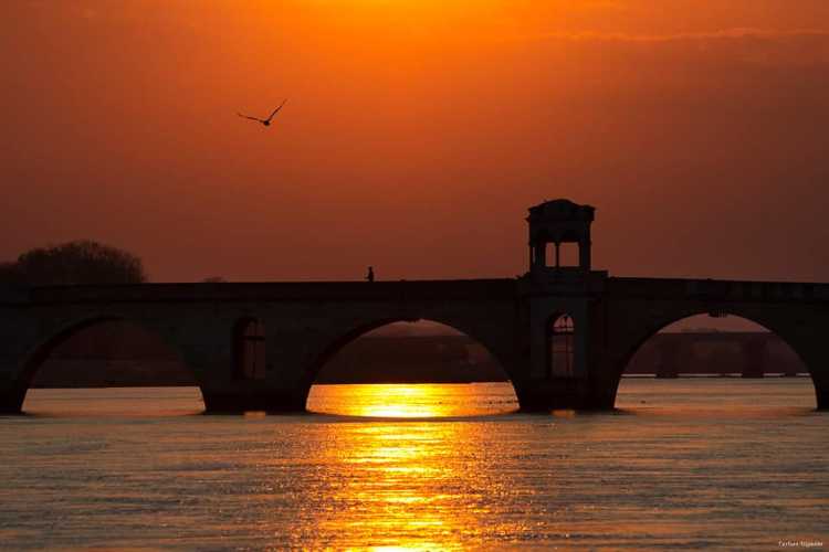 Mecidiye (Meriç) Bridge in Edirne at sunset, with sunlight streaming through the arches