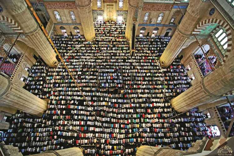 High-angle view inside Selimiye Mosque in Edirne showing worshippers gathered in prayer beneath the grand dome