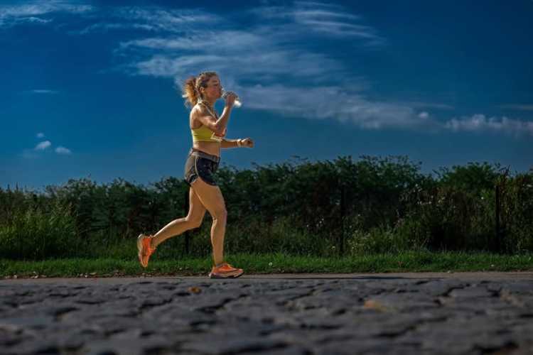 Young female runner holding a water bottle during the 10th International Edirne Marathon with greenery alongside the path