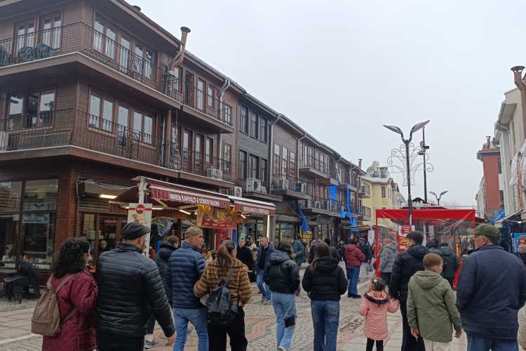 People walking on Saraçlar Street with traditional two-story wooden buildings in Edirne