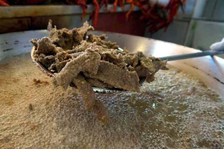 Thin slices of liver frying in hot oil in a pan while preparing Edirne fried liver (Tava Ciğeri)