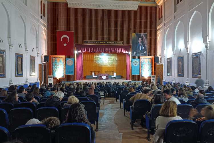 Audience seated from back rows to front at Edirne Hakl Eğitim Cultural Center, watching a play as the curtain opens