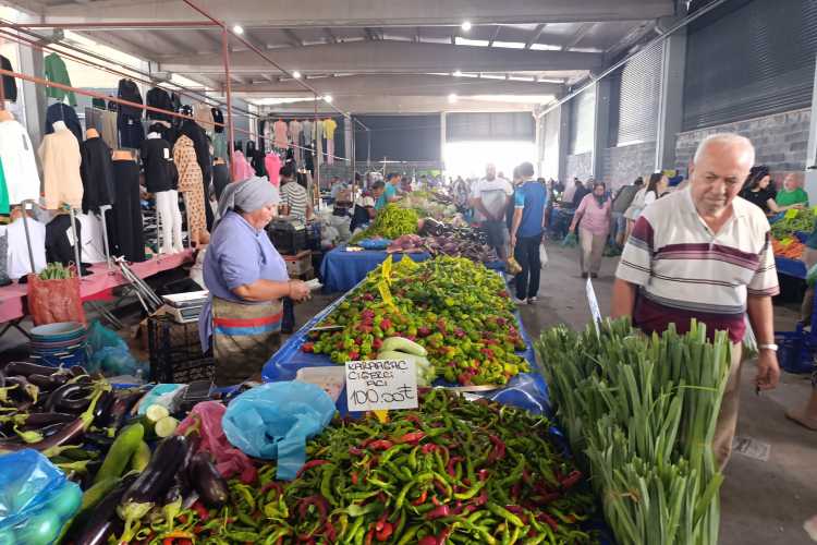 A man walking along vegetable stalls inside Edirne Cumartesi Pazarı market