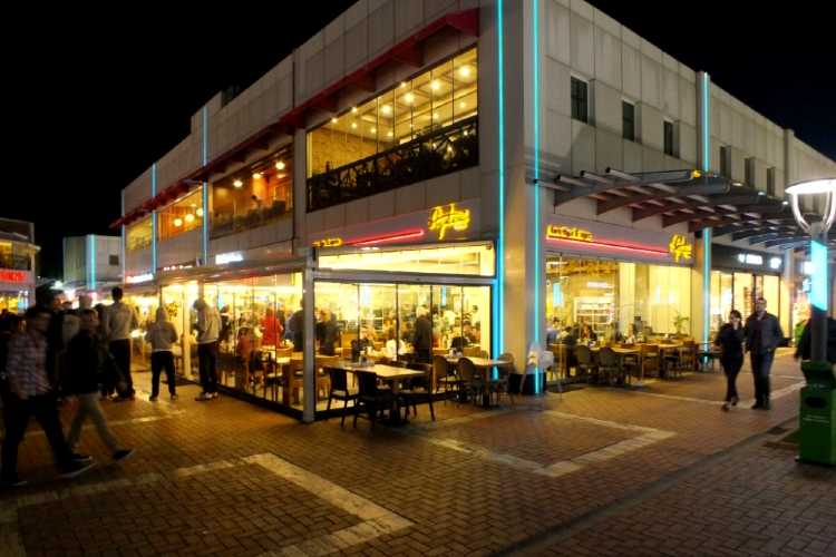 Open-air pedestrian shopping streets at Margi Shopping Center in Edirne with shops on both sides of narrow walkways and evening lighting