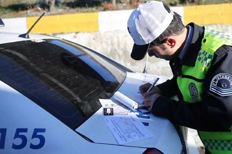 Traffic police officer writing a traffic ticket on the trunk of a police patrol car.