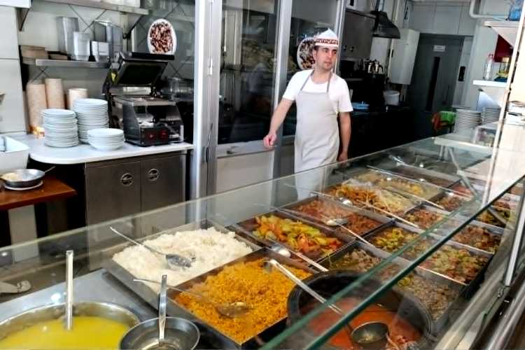 Chef behind hot food counter in Ustam Restaurant Edirne with various traditional dishes