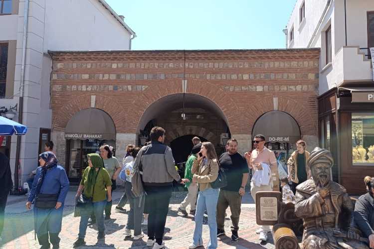 Exterior entrance of Ali Paşa Bazaar in Edirne historic Ottoman market with people entering and walking in the street in front of the gate
