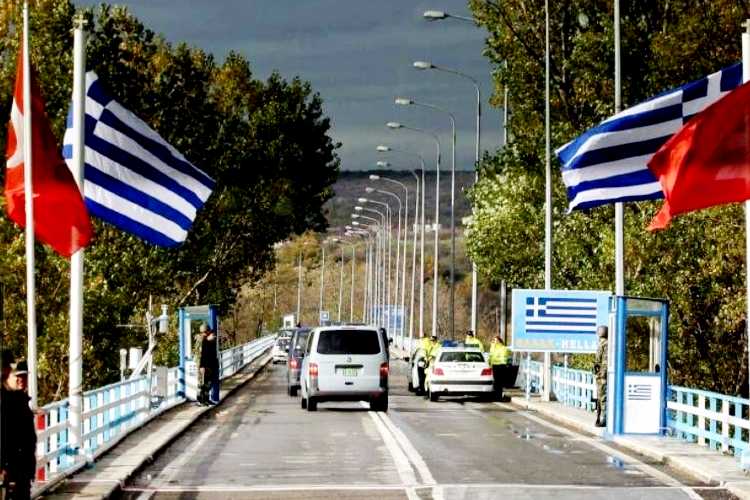 Vehicles passing through the İpsala Border Gate from Turkey to Greece, with Turkish and Greek flags visible on both sides of the crossing road.