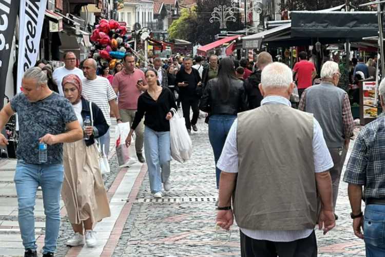 Busy street in Edirne with many pedestrians, including tourists, walking and shopping along a lively commercial area.