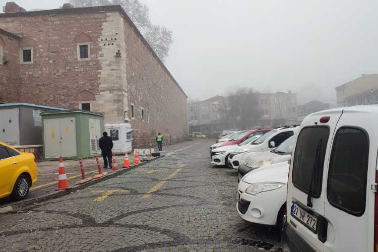 Public parking area in Edirne with parked cars along a street next to an old historic wall.