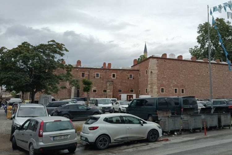 Municipal parking area in Edirne with several cars parked in front of a large historic building wall.