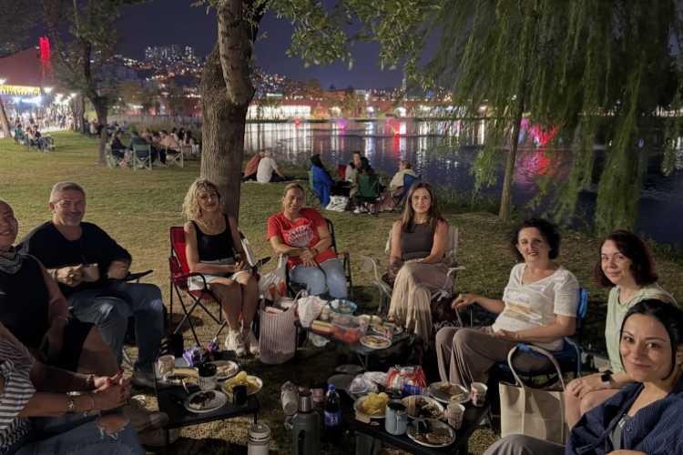 A group of people enjoying coffee and conversation outdoors in nature