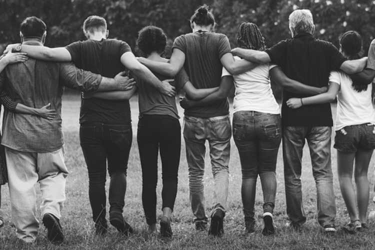 A group of friends walking in nature with their arms around each other's shoulders